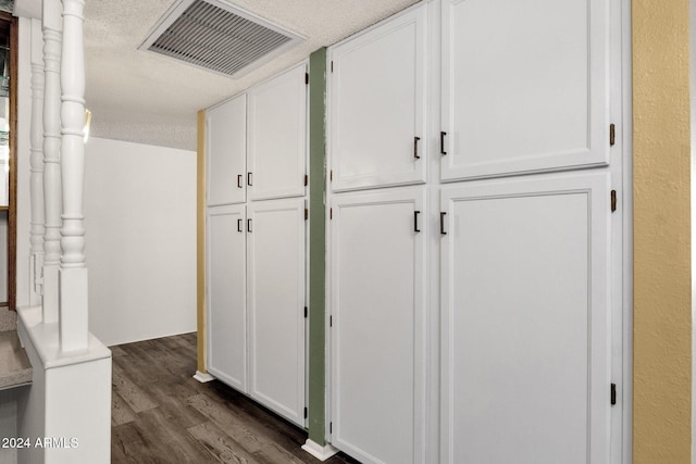 hall with a textured ceiling and dark hardwood / wood-style floors