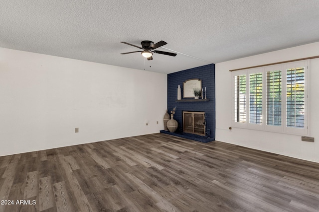 unfurnished living room with a textured ceiling, ceiling fan, dark hardwood / wood-style floors, and a brick fireplace