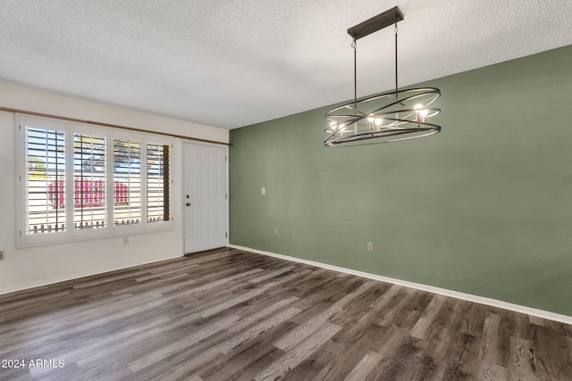 unfurnished dining area with a textured ceiling, dark hardwood / wood-style floors, and a notable chandelier