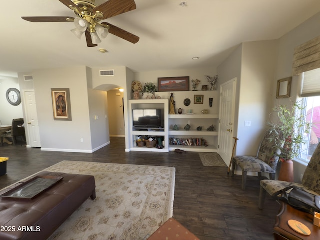 living area featuring wood finished floors, visible vents, arched walkways, and ceiling fan