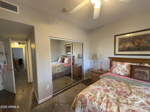 bedroom featuring visible vents, ceiling fan, baseboards, dark wood-style floors, and a closet