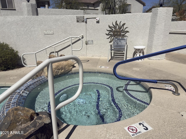 view of swimming pool with a community hot tub and fence