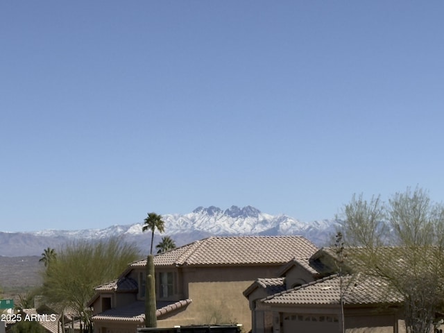 view of side of home featuring a mountain view, a garage, stucco siding, and a tiled roof