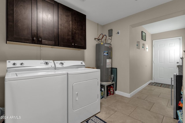 washroom with electric water heater, washer and clothes dryer, light tile patterned floors, and cabinets