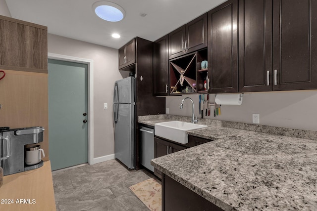 kitchen featuring dark brown cabinets, light stone countertops, sink, and stainless steel appliances