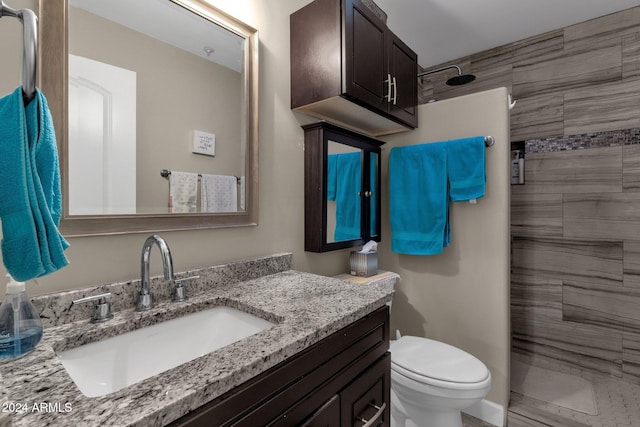 bathroom featuring vanity, toilet, and tiled shower