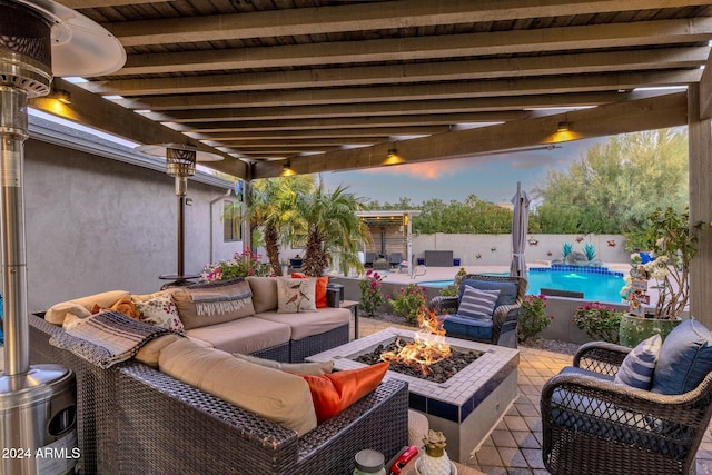 patio terrace at dusk with a fenced in pool and an outdoor living space with a fire pit