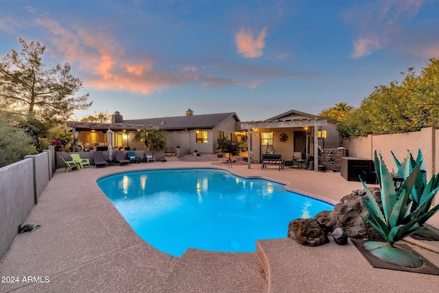 pool at dusk with outdoor lounge area and a patio area