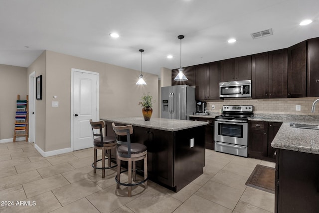 kitchen with a center island, stainless steel appliances, hanging light fixtures, and sink