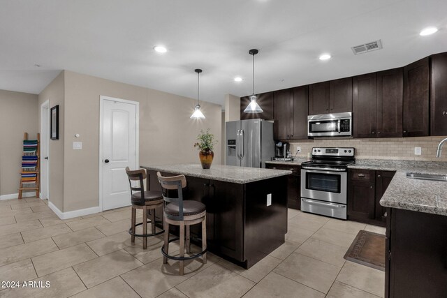 15019 N Mayflower Dr, Fountain Hills, AZ 85268 - kitchen with stainless steel appliances, a sink, a center island, backsplash, and dark brown cabinetry