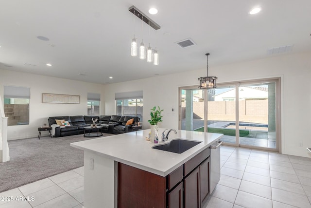 kitchen featuring sink, hanging light fixtures, a center island with sink, stainless steel dishwasher, and light colored carpet