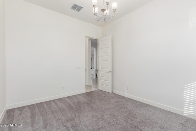 spare room featuring an inviting chandelier and light colored carpet