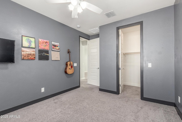 carpeted bedroom with a walk in closet, a closet, and ceiling fan