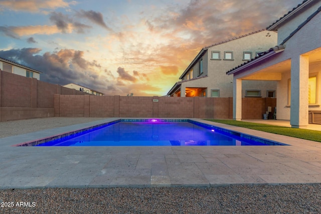 pool at dusk featuring a patio