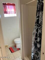 bathroom with toilet, tile patterned flooring, and a shower with shower curtain