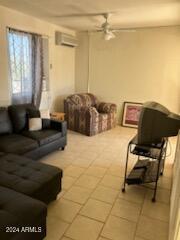 tiled living room featuring a wall mounted air conditioner and ceiling fan