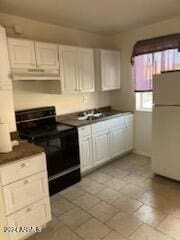 kitchen featuring black electric range oven, white cabinetry, and white refrigerator