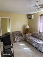 living room featuring a wall mounted air conditioner and ceiling fan