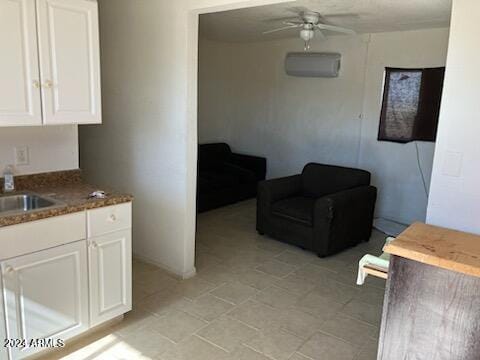 kitchen featuring white cabinetry, ceiling fan, sink, and a wall mounted air conditioner