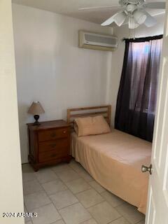 tiled bedroom with a wall mounted AC and ceiling fan