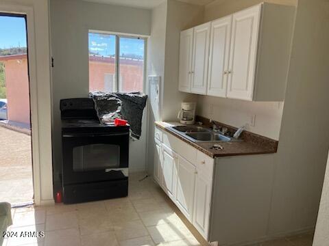 kitchen featuring a wealth of natural light, black range oven, and white cabinetry