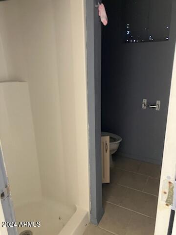 bathroom with toilet, walk in shower, and tile patterned flooring