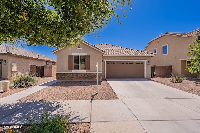 view of front of home with stucco siding, a tiled roof, concrete driveway, an attached garage, and fence