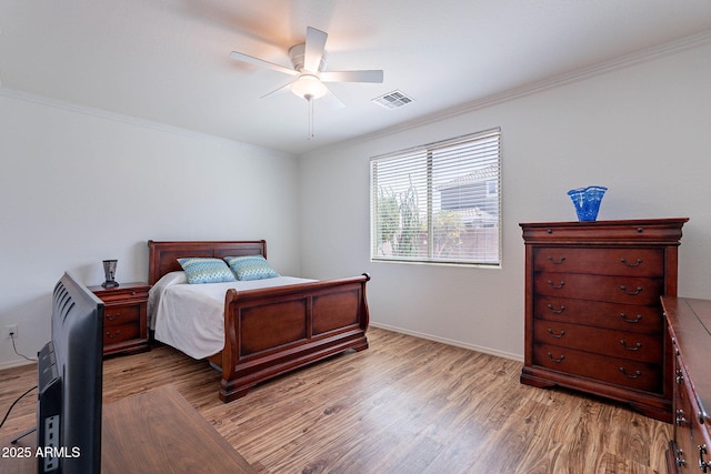 bedroom with light wood-style floors, ornamental molding, ceiling fan, baseboards, and visible vents