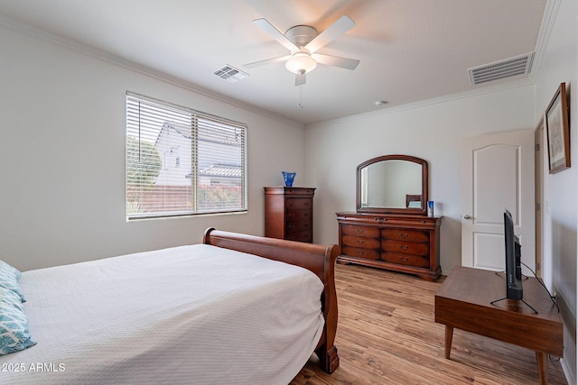 bedroom with crown molding, a ceiling fan, visible vents, and wood finished floors