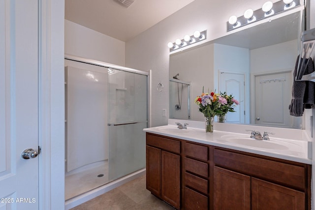 bathroom featuring double vanity, tile patterned flooring, a stall shower, and a sink