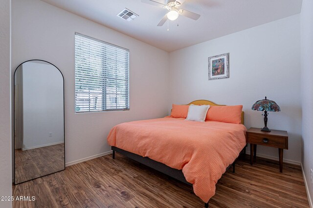 bedroom featuring baseboards, visible vents, wood finished floors, and a ceiling fan
