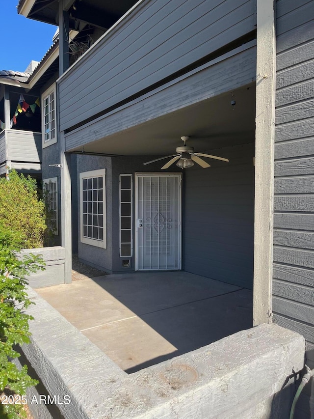 view of exterior entry featuring ceiling fan and a patio