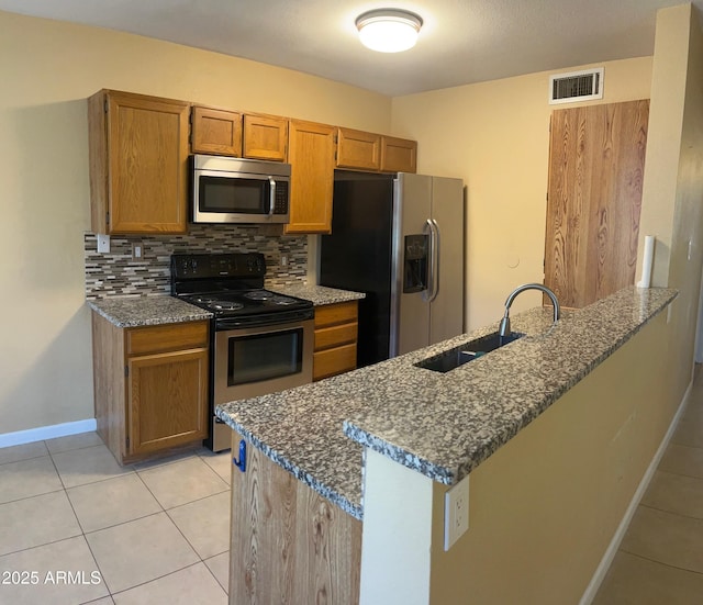 kitchen featuring appliances with stainless steel finishes, dark stone countertops, decorative backsplash, sink, and kitchen peninsula