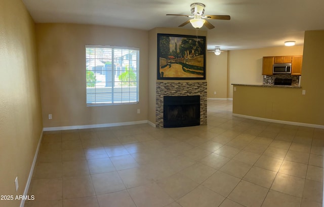 unfurnished living room featuring a fireplace, ceiling fan, and light tile patterned floors