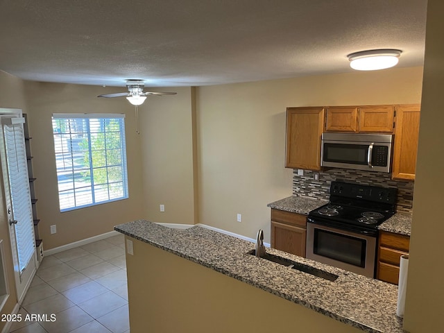 kitchen featuring stainless steel appliances, sink, backsplash, light tile patterned floors, and stone countertops