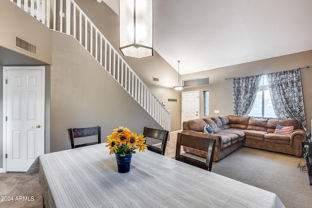 carpeted dining space with high vaulted ceiling