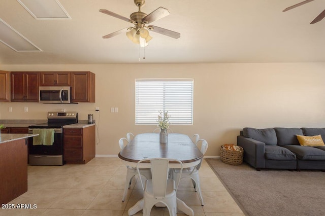 dining space featuring light tile patterned floors, ceiling fan, baseboards, and attic access