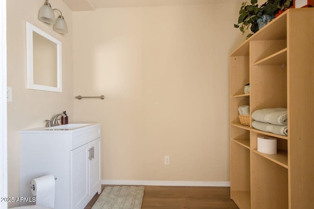 bathroom with baseboards, wood finished floors, and vanity