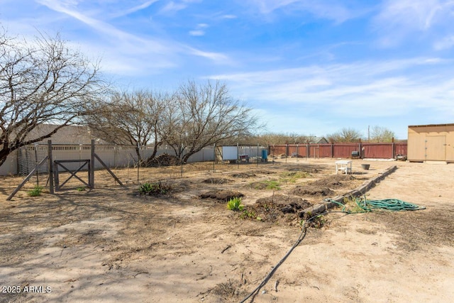 view of yard featuring a shed, a gate, an outdoor structure, and fence