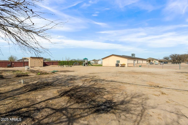 view of yard with an outbuilding, fence, playground community, and a shed