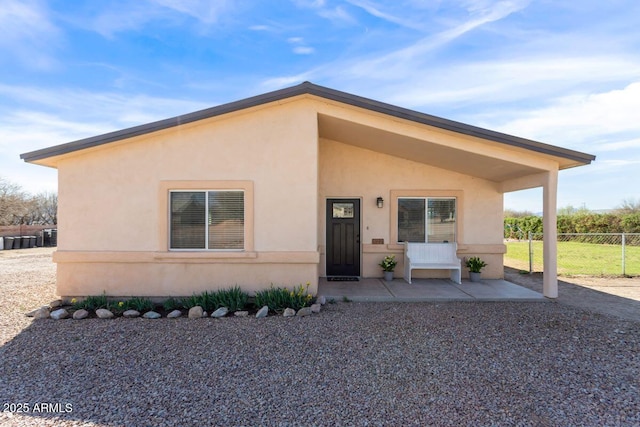 view of front facade with stucco siding and fence