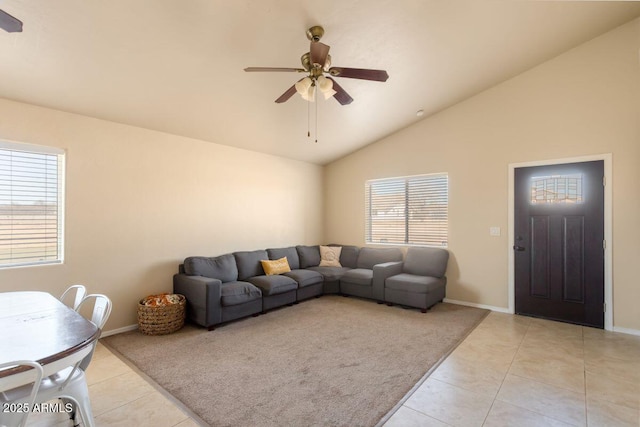 living area with a ceiling fan, light tile patterned floors, baseboards, and vaulted ceiling