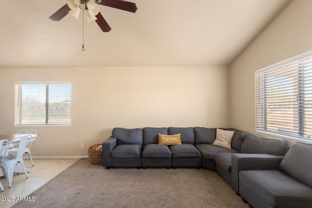 living area with lofted ceiling, light colored carpet, light tile patterned floors, baseboards, and ceiling fan