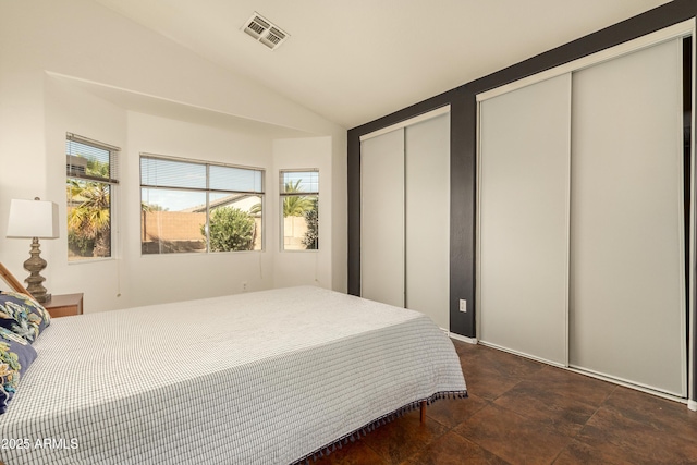 bedroom featuring vaulted ceiling, visible vents, and multiple closets