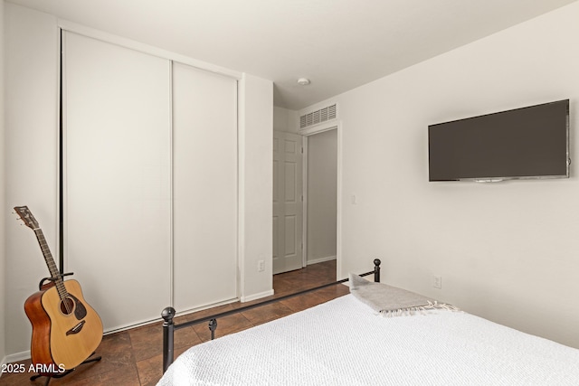 bedroom featuring a closet, visible vents, and stone finish floor