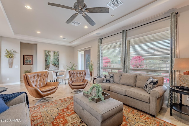 living room featuring a tray ceiling and ceiling fan