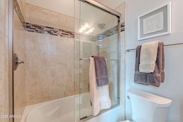 bathroom featuring toilet and combined bath / shower with glass door