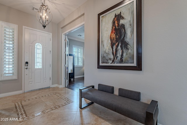 tiled entrance foyer featuring an inviting chandelier and crown molding