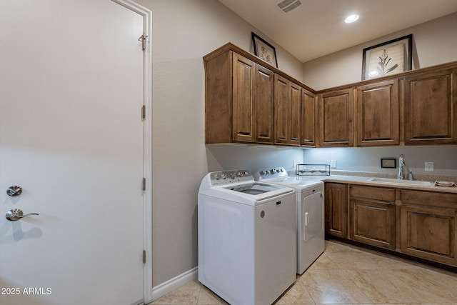 clothes washing area featuring light tile patterned flooring, cabinets, washer and clothes dryer, and sink