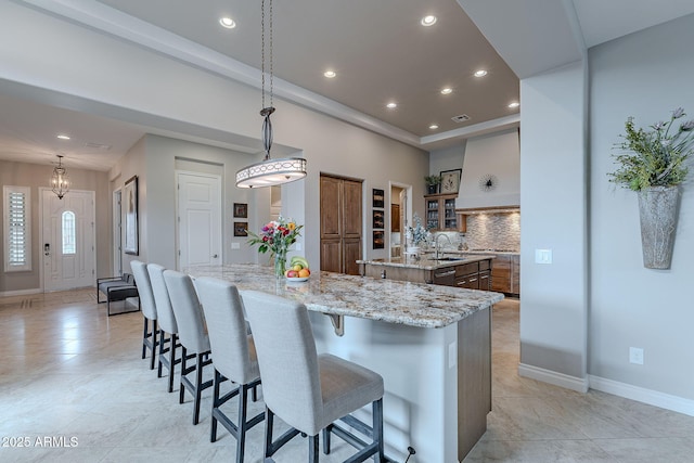 kitchen with tasteful backsplash, sink, decorative light fixtures, and a spacious island